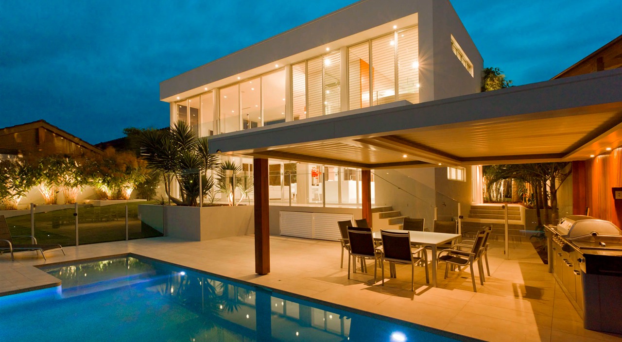 Casa de alto padrão à noite com iluminação integrada, piscina e área externa — projeto de automação residencial